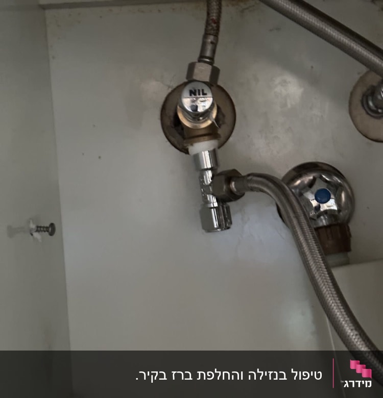 צינורות מתכת וברז מתחת לכיור